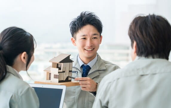 住宅模型を手に説明する株式会社ひだまり建設の担当者