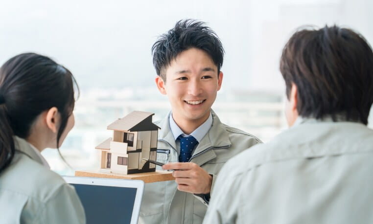 住宅模型を手に説明する株式会社ひだまり建設の担当者