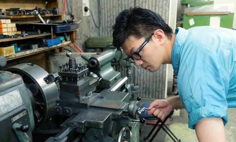 工作機械に向かって作業する有限会社 橘製作所の職人