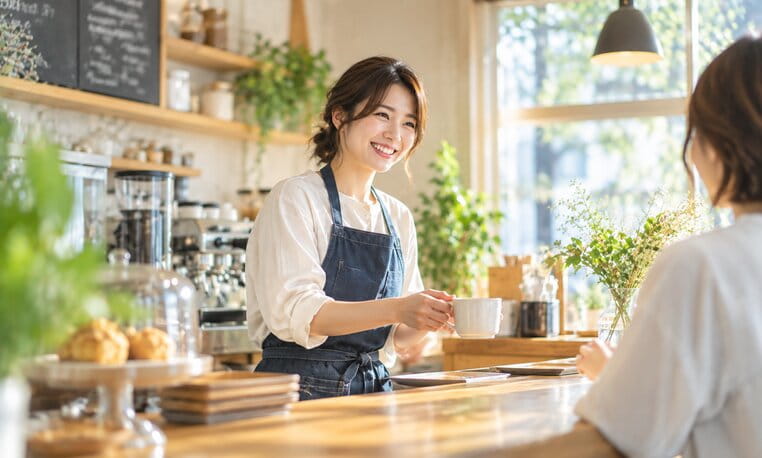 カウンター越しにお客様へコーヒーを出す cafe hinata のスタッフ